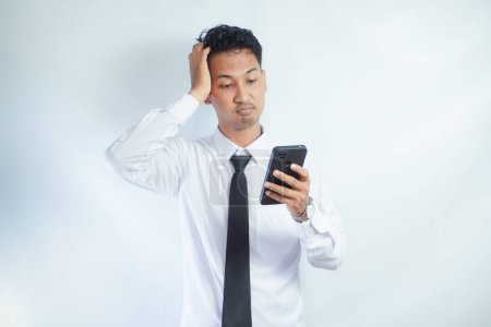 Photo for Adult Asian man showing stress expression when answering a phone call - Royalty Free Image