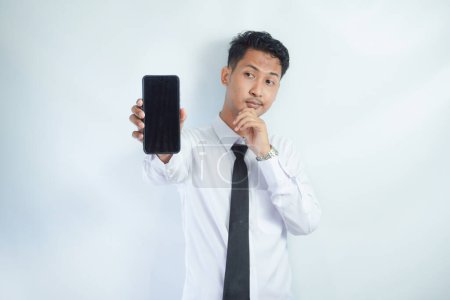 Erwachsener asiatischer Mann steht lächelnd und zeigt leeren Handybildschirm, den er in der Hand hält