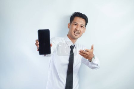 Adulto asiático hombre sonriendo confiado mientras señala el dedo a la pantalla del teléfono en blanco