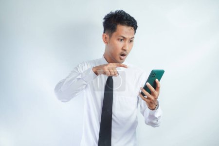 Erwachsener asiatischer Mann zeigt Wutausdruck, wenn er auf sein Handy schaut