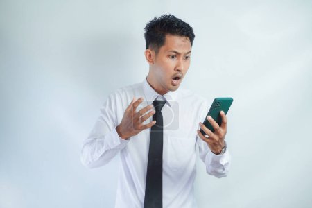 Erwachsener asiatischer Mann zeigt Wutausdruck, wenn er auf sein Handy schaut
