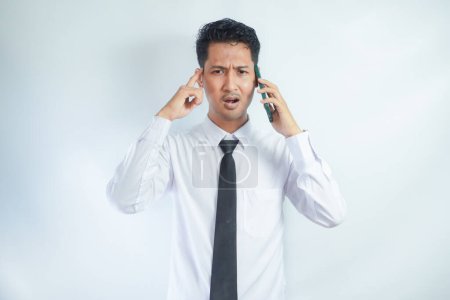 Photo for Adult Asian man showing not happy expression when answering a phone call - Royalty Free Image