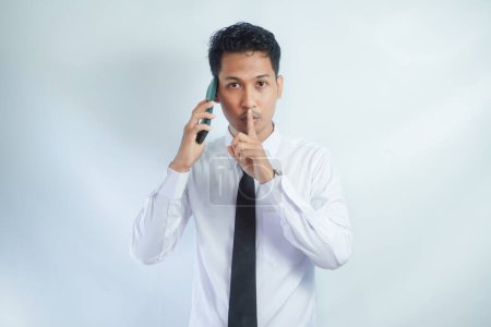 Office worker showing keep silent gesture while making a call