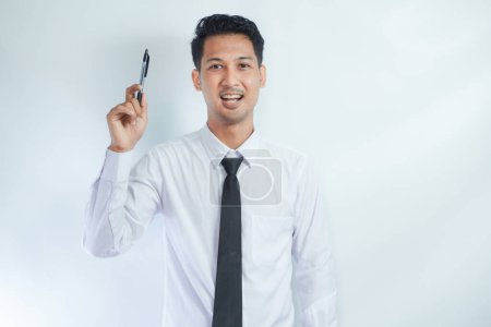 Young Asian businessman smiling and pointing finger up while holding a book