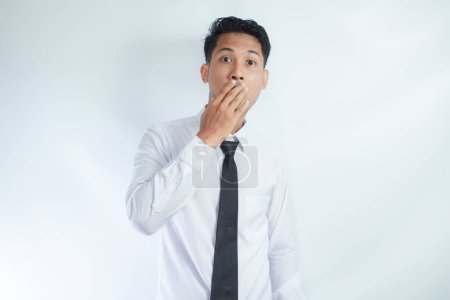 Kopfschuss eines verängstigten jungen asiatischen Geschäftsmannes, der den Mund bedeckt und mit verängstigtem Gesichtsausdruck in die Kamera schaut, aus Angst, bei der Arbeit gefeuert zu werden