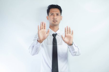 Adult Asian businessman looking camera and give stop hand sign with serious face expression