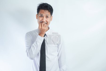 Imagen de aterrorizado joven empresario asiático cubriendo la boca y mirando a la cámara con expresión de miedo en su cara, temeroso de ser despedido fracaso en el trabajo