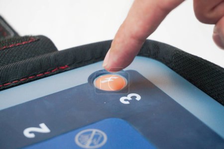 presionando el botón de choque del DEA para entregar un choque eléctrico a un paciente con ataque cardíaco