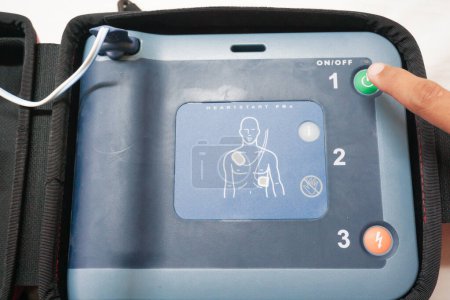 Téléchargez les photos : Appuyer sur le bouton d'alimentation AED pour l'allumer et utiliser un patient en arrêt cardiaque - en image libre de droit