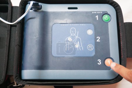 Photo for Pressing the AED's shock button to deliver an electric shock to a heart attack patient - Royalty Free Image