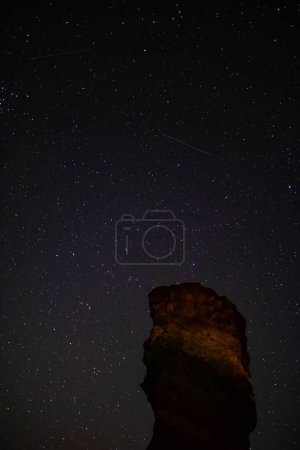Foto de El cielo estrellado y las estrellas fugaces en el fondo, donde se puede distinguir una formación rocosa típica en España y especialmente en el Teide. - Imagen libre de derechos