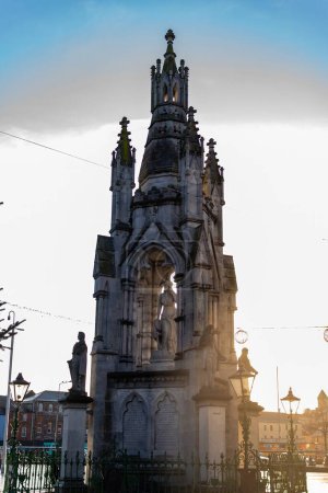 Foto de Silueta de un monumento gótico contra un cielo atardecer con elementos urbanos en primer plano. - Imagen libre de derechos