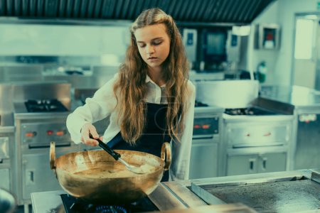 Foto de En la escuela culinaria, los adolescentes aprenden de los chefs reales cómo hacer tipos de comida de buen gusto. Cocinar espaguetis es una práctica práctica práctica que involucra el sentido del gusto y el olfato de los estudiantes mientras siguen recetas. - Imagen libre de derechos