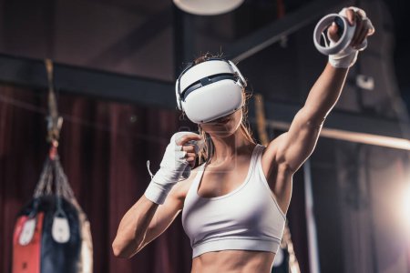 Téléchargez les photos : Les amateurs de fitness se battent contre d'autres membres du gymnase en portant des lunettes de réalité virtuelle lors d'exercices intenses de boxe. Apprendre et améliorer les techniques de boxe, des simples frappes aux combos complexes - en image libre de droit