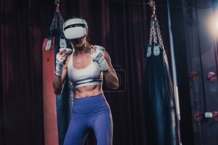 Photo for Fitness lovers battle against other gym members by wearing virtual reality goggles during intense boxing exercises. Learning and improving boxing techniques, from simple strikes to complex combos - Royalty Free Image