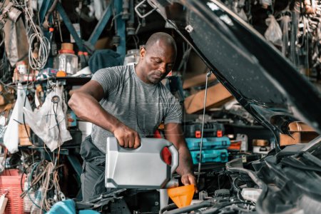 Photo for Auto mechanic diagnose and troubleshoots with tools and equipment. Polishing car, fixing braking and steering systems. Measuring oil levels with oil gauge stick and then pouring or changing it. - Royalty Free Image
