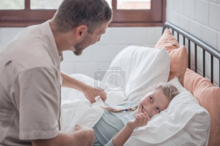 Photo for Father singing his daughter to sleep, providing comfort, support, and security. Focusing on fulfilling both physical and emotional needs. Kids sometimes act happy while pretending to fall asleep. - Royalty Free Image