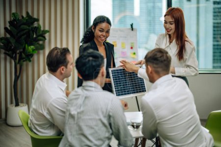Téléchargez les photos : In multicultural workspace, innovative project manager present sustainable solar panel product, fostering collaboration and diversity among colleagues, aiming for efficient, renewable energy solution - en image libre de droit