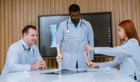 Photo for A multicultural boardroom discussion between the surgeon, radiologist on patient's case of ankle injuries. They examine, analyze MRI scans for the most effective, precise treatment plan and procedure - Royalty Free Image