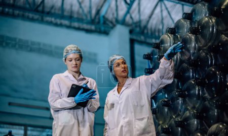 Photo for Experienced manufacturing supervisor coaches and mentors trainee in quality control. Examining sequence, inventory, physical standard for precise and effective seamless of drinking water distribution - Royalty Free Image