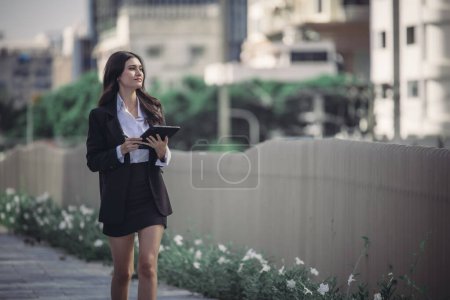 Photo for A determined and confident executive woman proudly leads organization, exemplifying exceptional leadership, commitment, strategic thinking while overseeing daily operations with her tablet in hand. - Royalty Free Image