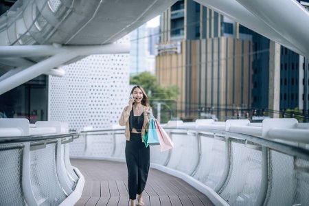 Photo for Fashionable young lady enjoys her weekend by taking a leisurely stroll through downtown, checking out the newest department stores, and smiling broadly the whole time. Enjoying in stylish attires. - Royalty Free Image