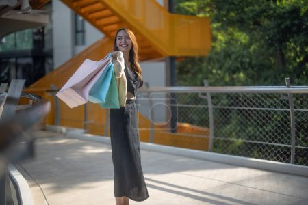 Photo for Fashionable young lady enjoys her weekend by taking a leisurely stroll through downtown, checking out the newest department stores, and smiling broadly the whole time. Enjoying in stylish attires. - Royalty Free Image