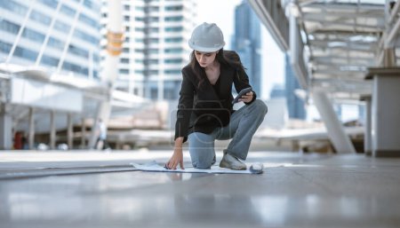 Photo for Skilled female architect meticulously inspects building site on and around Skytrain, cross referencing the blueprint and architectural layout. Implementing precise calculations for project approval. - Royalty Free Image