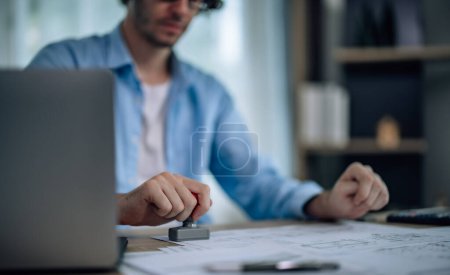 Photo for The project manager of startup company agree to signs proposal and uses a rubber stamp to authorize the project's implementation. A leadership that is open-minded, supportive, ethical and transparent - Royalty Free Image