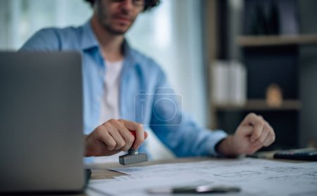 Photo for The project manager of startup company agree to signs proposal and uses a rubber stamp to authorize the project's implementation. A leadership that is open-minded, supportive, ethical and transparent - Royalty Free Image