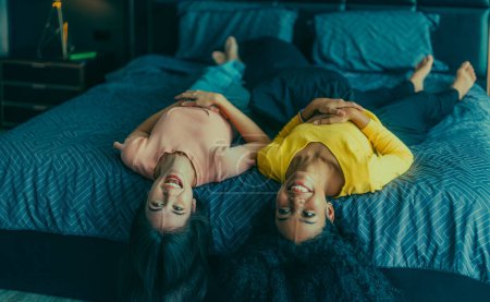Foto de Amantes de las lesbianas participan en interacciones lúdicas en la cama. Sus ojos se encuentran con una mirada afectuosa, irradiando amor y ternura. Riendo, compartiendo momentos íntimos llenos de calidez y alegría. - Imagen libre de derechos