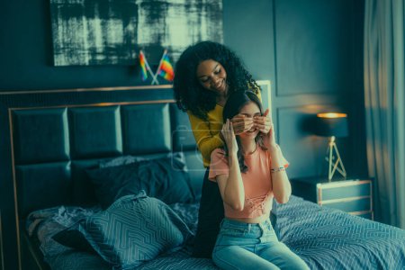 Photo for Lesbian lovers engage in playful interactions on bed. Their eyes meet with an affectionate gaze, radiating love and tenderness. Laughing, sharing intimate moments filled with warmth and playfulness. - Royalty Free Image