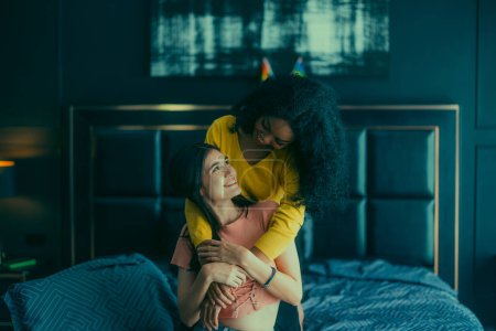 Téléchargez les photos : Les amateurs de lesbiennes s'engagent dans des interactions ludiques sur le lit. Leurs yeux rencontrent un regard affectueux, rayonnant d'amour et de tendresse. Rire, partager des moments intimes remplis de chaleur et de ludique. - en image libre de droit