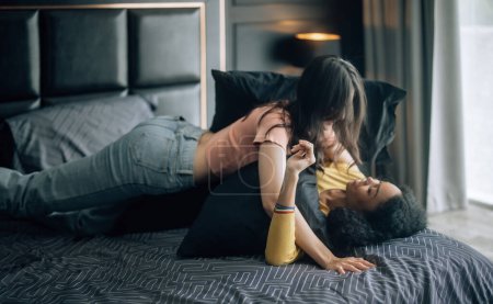Foto de Las parejas lesbianas participan en momentos lúdicos en la cama acogedora, su risa llena el aire, creando un ambiente de alegría y afecto. Abrazan, comparten tiernos besos, mostrando felicidad genuina. - Imagen libre de derechos