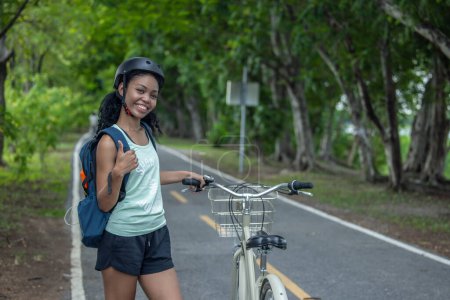 Téléchargez les photos : Femme cycliste combiner éco-conscience avec un mode de vie actif, en utilisant des vélos pour l'entraînement et les voyages, un panneau solaire portable pour la charge de l'appareil, et embrasser les pratiques de recyclage pour l'économie circulaire. - en image libre de droit