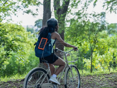 Foto de Las ciclistas combinan la conciencia ecológica con el estilo de vida activo, el uso de bicicletas para hacer ejercicio y viajar, un panel solar portátil para cargar dispositivos y las prácticas de reciclaje para la economía circular. - Imagen libre de derechos