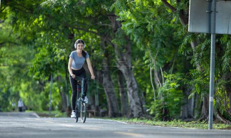 Téléchargez les photos : Femme cycliste combiner éco-conscience avec un mode de vie actif, en utilisant des vélos pour l'entraînement et les voyages, un panneau solaire portable pour la charge de l'appareil, et embrasser les pratiques de recyclage pour l'économie circulaire. - en image libre de droit