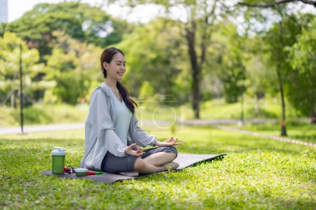 Photo for Young adult Asian female discovers revitalization through engaging in park yoga and meditation practices. Aligning physical, mental abilities Restoring energy levels, overall vitality, and well-being - Royalty Free Image