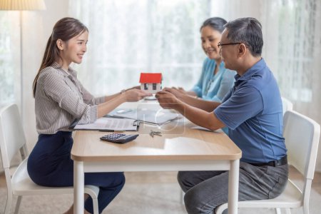 Photo for Elderly couples satisfying service in purchasing retirement residence. A detailed contract with saleswoman ensures a smooth transition, including key handovers after agreement on terms and conditions - Royalty Free Image
