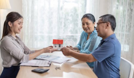 Photo for Elderly couples satisfying service in purchasing retirement residence. A detailed contract with saleswoman ensures a smooth transition, including key handovers after agreement on terms and conditions - Royalty Free Image