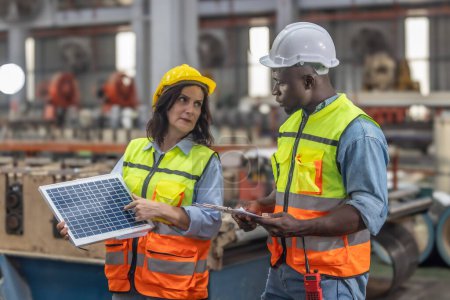 Foto de Trabajadores de chapa metálica en fábrica planean instalar paneles solares en el techo, promover la energía renovable, reducir costos, registrar créditos de carbono para una manera sostenible y eficiente de combatir el cambio climático. - Imagen libre de derechos
