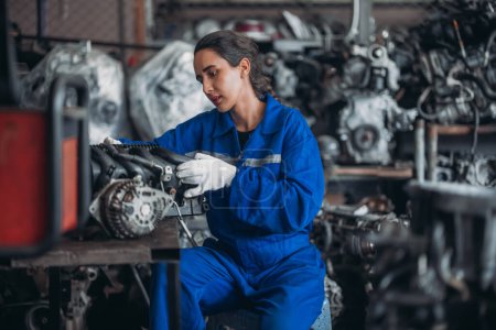 Photo for Car service technicians expertly inspect, assess engine parts in storage. Carefully selecting quality gears and instruments for precise repairs, modify, assembly. Assuring optimal vehicle performance - Royalty Free Image