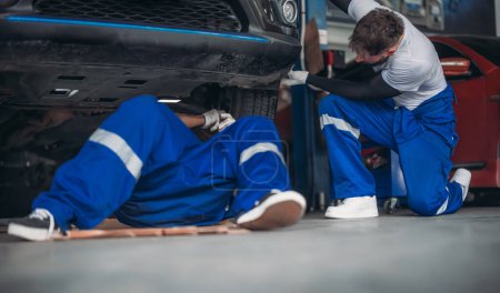 Photo for Car service technicians inspect, analyze, diagnose suspension system issues in garage with precise tools. Detect, troubleshoot, repair problems. Ensuring optimal vehicle performance and safety. - Royalty Free Image