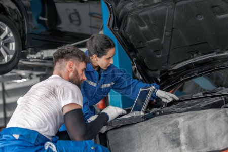 Photo for Skilled car service technicians utilize advanced computerized diagnostics and precise tools in garage workshop to analyze, troubleshoot, repair engine and system issues, ensuring optimal performance. - Royalty Free Image