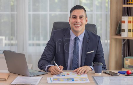 Photo for Portrait of male mixed race business manager wearing formal suit, using laptop, tablet to work in modern office. Completing routine tasks, talking with clients, analyzing, and approving projects. - Royalty Free Image