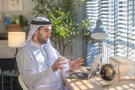 Photo for Sheikh, CEO in arb dress, supervising business, distant meetings, and communication via video call with the team with a smile gesture. Overseeing operations as a leader, showcasing responsibilities. - Royalty Free Image