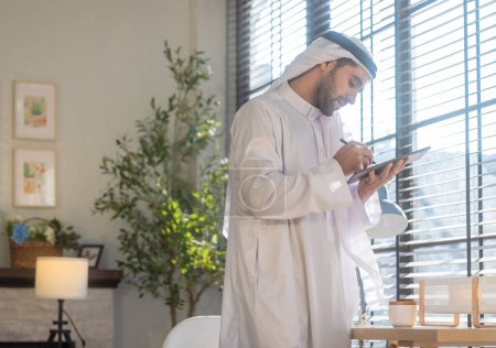 Sheikh, CEO en vestido árabe, supervisando negocios, reuniones a distancia, y la comunicación a través de videollamadas con el equipo con un gesto de sonrisa. Supervisar las operaciones como líder, mostrando responsabilidades.