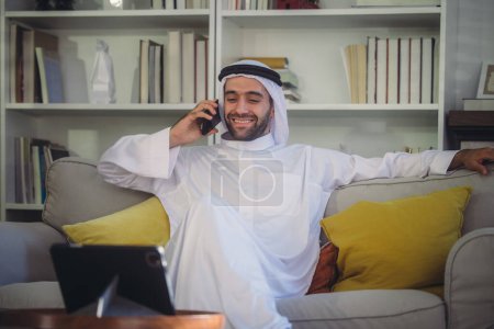 Téléchargez les photos : Cheikh, PDG en robe d'arb, supervisant les affaires, les réunions à distance et la communication par appel vidéo avec l'équipe avec un geste de sourire. Superviser les opérations en tant que leader, mettant en évidence les responsabilités. - en image libre de droit