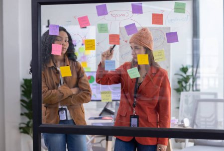 Photo for Multicultural startup team brainstorm, exchange ideas, develop fresh perspective by using sticky notes. Working collaboratively as a team help generate innovative idea, potential solution for company - Royalty Free Image