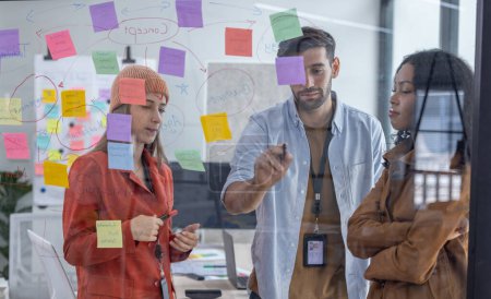 Photo for Multicultural startup team brainstorm, exchange ideas, develop fresh perspective by using sticky notes. Working collaboratively as a team help generate innovative idea, potential solution for company - Royalty Free Image